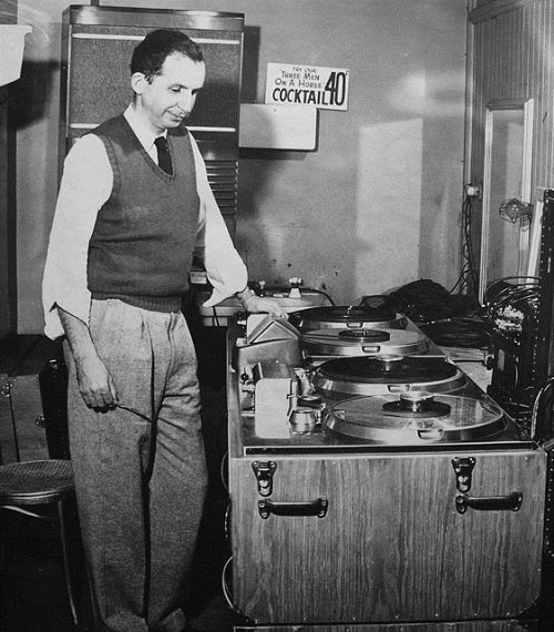 Jack Mullin, scissors in hand, looking over a pair of Ampex model 200s